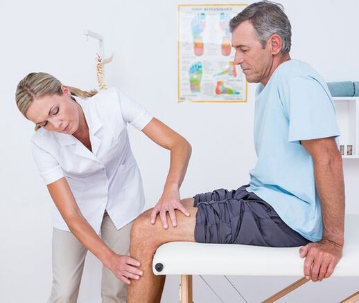 Il medico esegue un esame visivo e palpazione del paziente con dolore al ginocchio