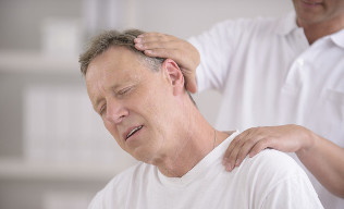 Un uomo con osteocondrosi del collo alla reception di un massaggiatore manuale